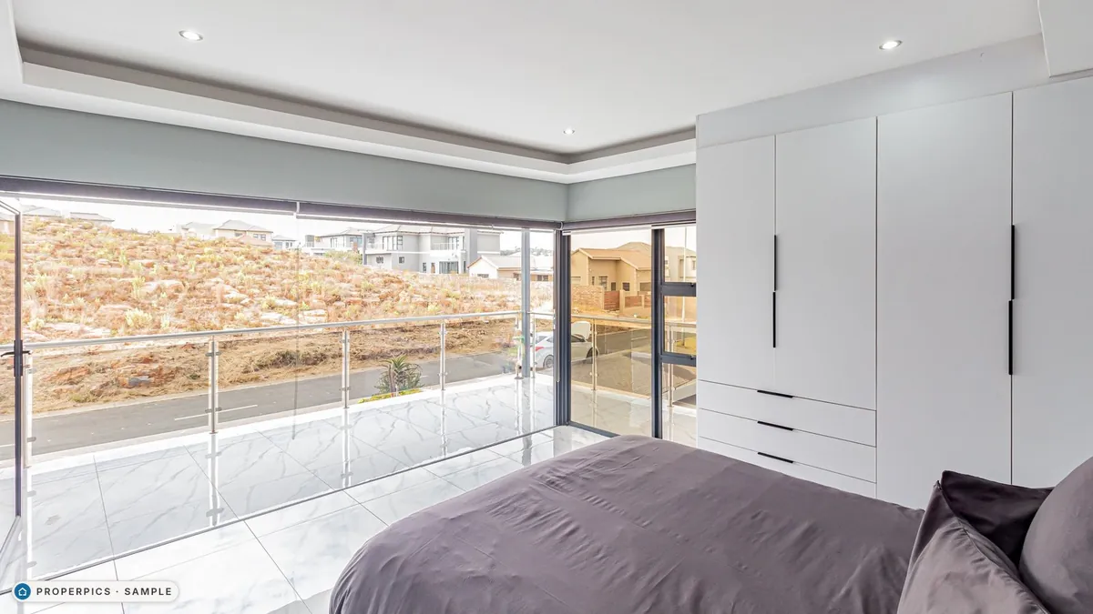 A bedroom as photographed from beside the bed, looking out to the view, with its own furniture