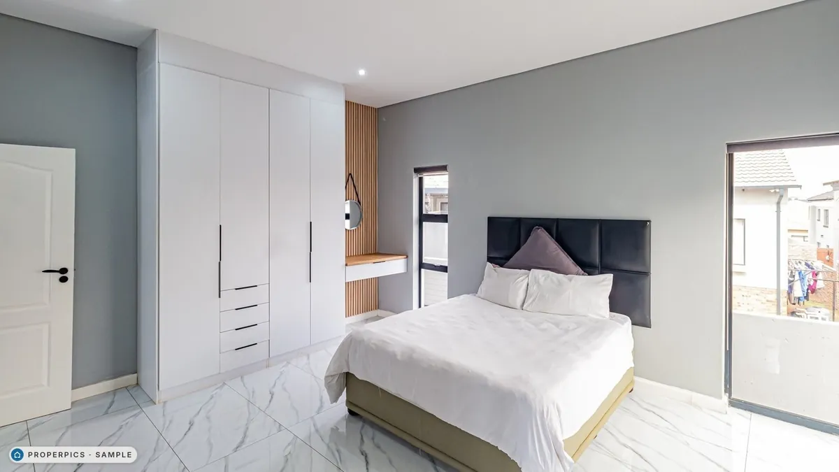 A bedroom as photographed from the side of the room, facing the cupboards, with its own furniture